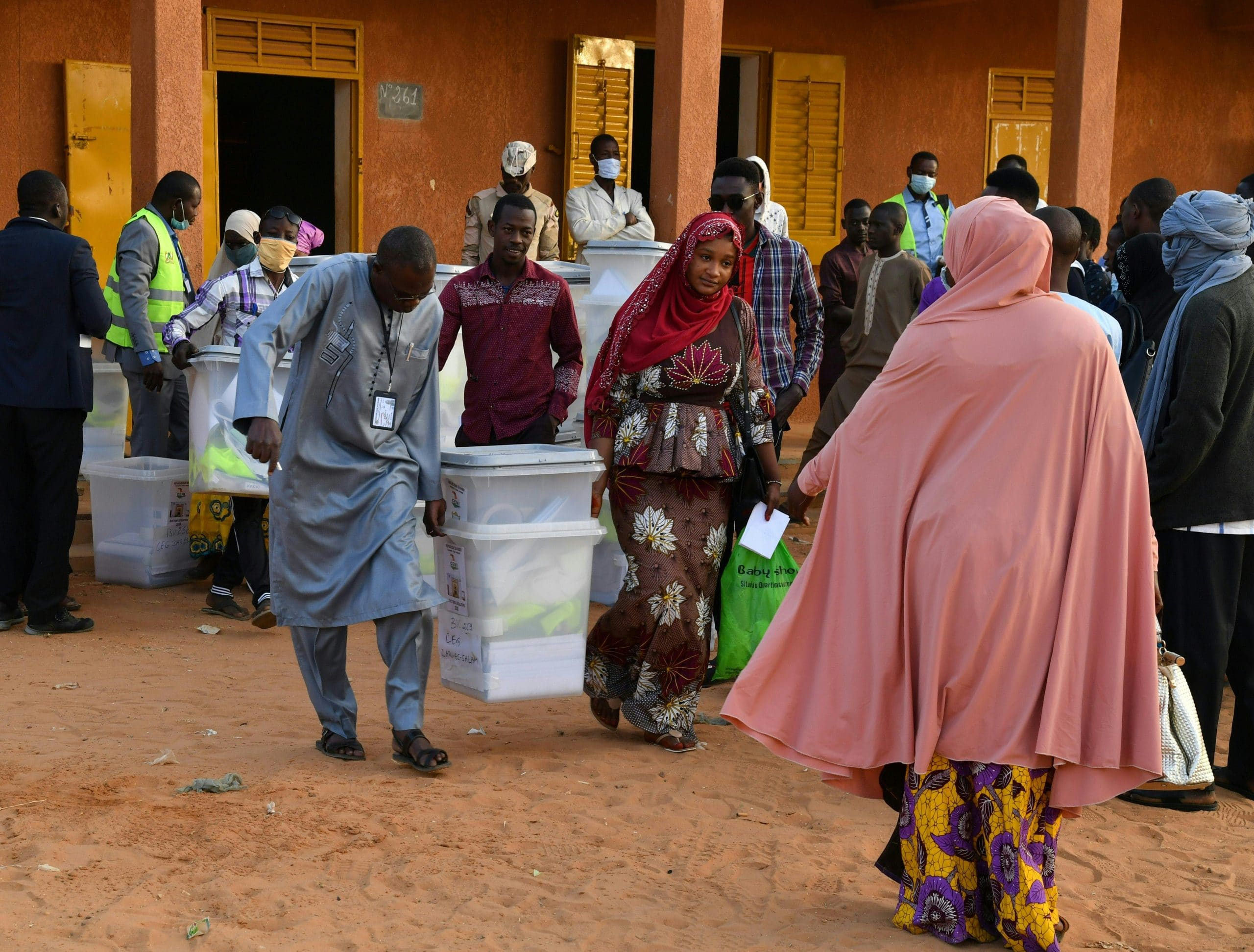 Des responsables de la commission électorale transportent des urnes devant un bureau de vote à Niamey le 27 décembre 2020 lors des élections présidentielles et législatives au Niger. - Les électeurs de l'État sahélien du Niger se rendent aux urnes le 27 décembre 2020 pour une élection qui pourrait sceller la toute première passation de pouvoir pacifique du pays entre les présidents élus, malgré une insurrection djihadiste sanglante. (Photo par Souleymane AG ANARA / AFP)
